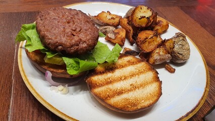 Open Burger on a Plate with Side of Crispy Potatoes – A Delicious Meal