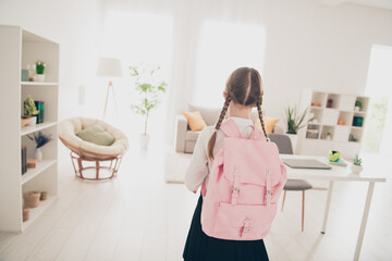 Rear portrait of lovely little schoolchild backpack wear uniform living room flat indoors