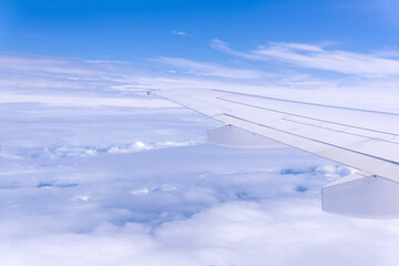 view from airplane window during flight, wing and cloudscape, view above clouds