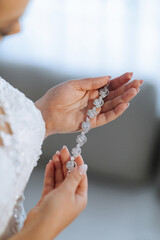 A woman is holding a necklace with a large diamond pendant. The necklace is made of silver and has...