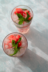 Homemade summer watermelon lemonade with ice and mint on light background, place for text