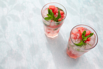 Homemade summer watermelon lemonade with ice and mint on light background, place for text