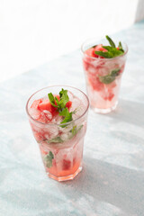 Homemade summer watermelon lemonade with ice and mint on light background, place for text