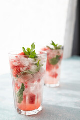 Homemade summer watermelon lemonade with ice and mint on light background, place for text