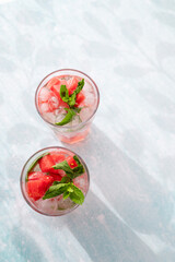Homemade summer watermelon lemonade with ice and mint on light background, place for text