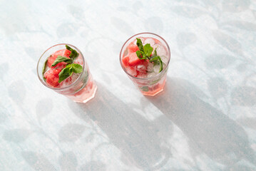 Homemade summer watermelon lemonade with ice and mint on light background, place for text