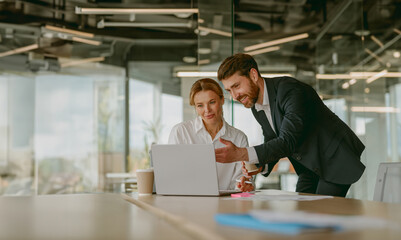 In a sleek and modern office setting, two professionals are actively engaged in a collaborative task