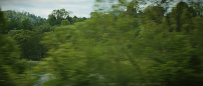 View from a car window or train on river and landscape outside on a summer day. Green tree and blue sky