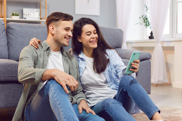 Obraz premium Married couple spends leisure time together at home, using a phone for online entertainment and communication. This moment highlights enjoyment of the internet and each other's company.
