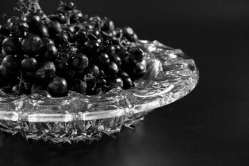 Black image of champagne grapes on glass bowl. Close-up a bunch of beautiful grapes with concept of fine art, still-life food, fruit, dark, noise, luxury, elegant wallpaper. Abstract grapes on black.