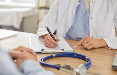 Close up of a doctor hands with a stethoscope on the table during a medical consultation with a...