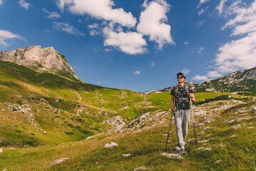 Fototapeta premium Woman Hiker Walking with Hiking Poles on Mountains