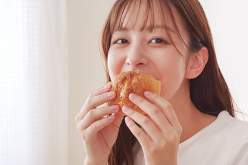 おやつのシュークリームを食べる女性