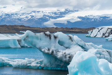 Joekulsarlon Glacier Lagoon Landscape with blue ice at south Iceland, background a mountain range with snow