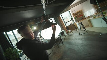 Young filmmaking man preparing studio for shooting. Installation of light equipment. Cinema production. Lighting device