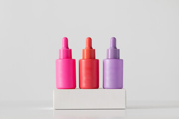 Bright colored vials with pipettes with anti-aging skin serum on podiums.