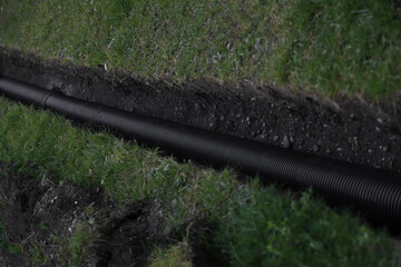 New black plastic corrugated water pipeline in trench. Replacement of old rusty tubes by new one,