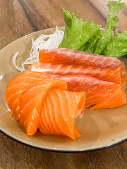 Fresh Sliced Salmon Sashimi is a Japanese specialty that uses fresh raw fish meat without bones, served with grated radish, zucchini, soy sauce, lime wedges, and wasabi.
