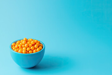 Vibrant orange balls in a blue bowl against a solid blue background, perfect for food-related themes and bright color compositions.