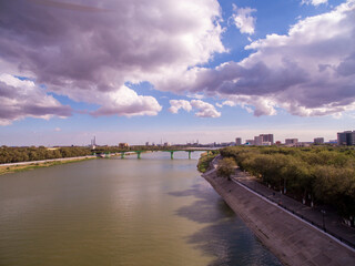 Fototapeta premium Bridge over the river at noon with red clouds in the sky