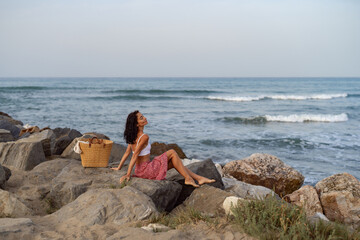 Woman Sitting on Rocks by the Sea