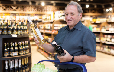 Elderly man choose bottle of alcohol