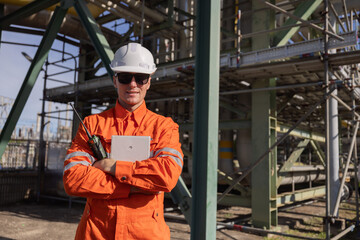 Engineer with cross arm pose at oil refinery site