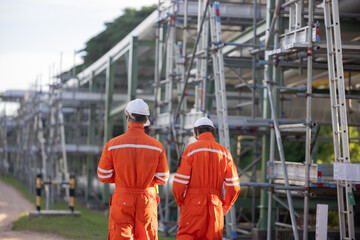 Engineer workers walking and discussing their work along along the oil refinery site