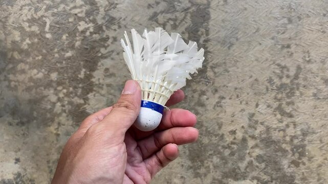 A man try to repair and tidy up the broken feathers of used shuttlecock which has been used repeatedly. Concept for Badminton Practice