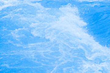 Blue water with ripples on the surface. Defocus blurred transparent blue colored clear calm water surface texture with splashes and bubbles. Water waves with shining pattern texture background.