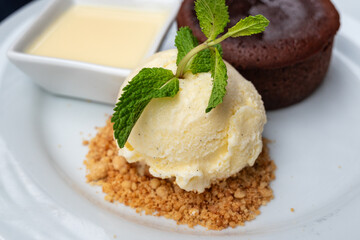 vanilla ice cream and sauce served as an addition to chocolate fudge brownie cake