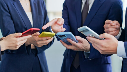 スマホを使うビジネスパーソンのグループ © metamorworks