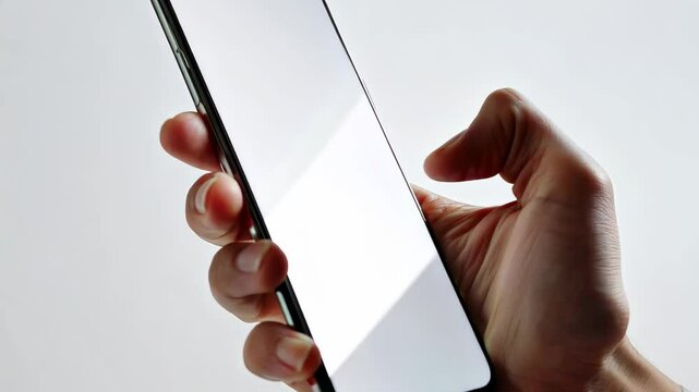 POV hand holding smartphone with blank white screen, isolated on light minimalist background