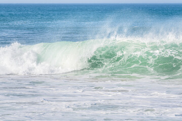 Enourmous ocean crashing wave throwing up plumes of spray on an windy day in autumn