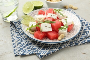 Delicious watermelon salad with feta cheese, cashew nuts and spices on light table