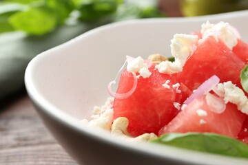 Tasty salad with watermelon, feta cheese and basil on wooden table, closeup