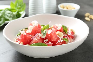 Tasty salad with watermelon, feta cheese and basil on black table