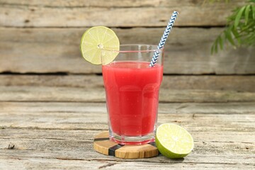 Tasty watermelon drink in glass and lime on wooden table