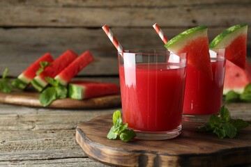 Tasty watermelon drink in glasses, fresh fruit and mint on wooden table