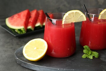 Delicious watermelon drink in glasses, fresh fruits and mint on grey table, closeup