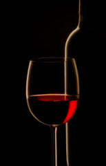 Red Wine Glass and Bottle on a black background close up.