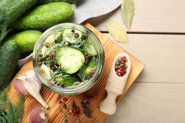 Making pickles. Fresh cucumbers and spices in jar on wooden table, top view
