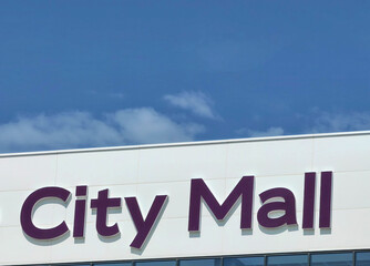 Time for Shopping: City Mall Signage on White Rooftop Building Against blue Cloudy Sky.