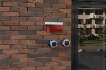 Two metal fire hydrant connections attached to a brick wall, ready for use in an emergency situation