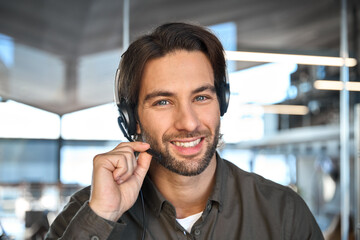 Portrait of happy young business man wearing headset, smiling young professional male customer care...