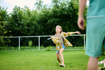 Teenage girl playing badminton with her father on green grass in summer park