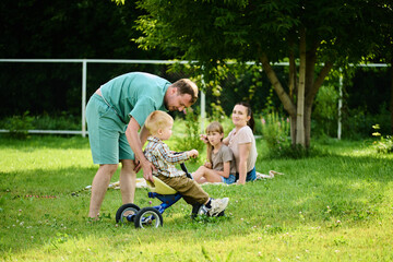 Happy Caucasian family on picnic having fun, eating and playing games on green grass