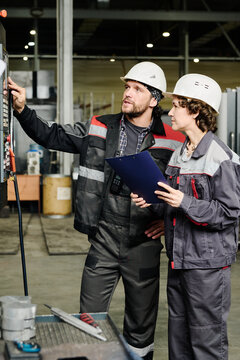 Two industrial workers, possibly an engineer and technician, discussing machine operations