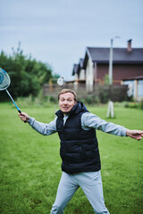 Happy family playing badminton on green grass in summer park