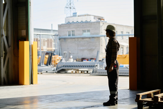 Engineer observing outdoor industrial site with various construction equipment in background